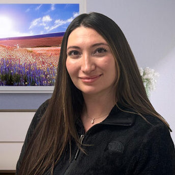 Caroline Peterson new patient coordinator with colorful meadow flower picture behind her
